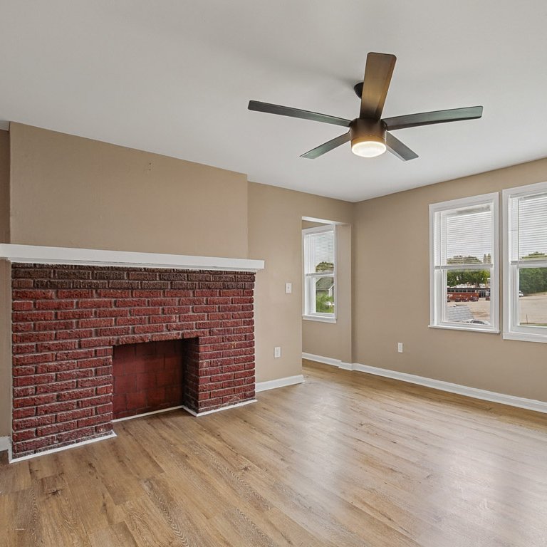 Renovated living room with a brick fireplace in a Montgomery Road fourplex unit in Norwood, Ohio
