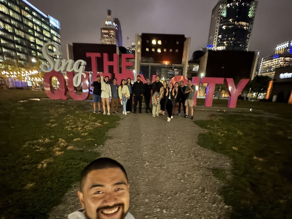 Field trip group at the Sing the Queen City sign at night